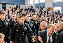 I spent fifteen years working exhausting shifts in frayed clothes just to see my only son graduate from the Naval Academy today. But before his name was called, two campus guards publicly humiliated me, grabbing my arm and attempting to eject me from the auditorium for looking out of place. Just as they shoved me toward the exit doors, ten decorated high-ranking officers suddenly rose from the front row, forcing everyone to freeze when they revealed who I truly was…