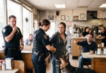 I was handcuffed in a crowded diner just for standing my ground, but the aggressive officer had no idea my dog carried a restricted federal record that changed everything.